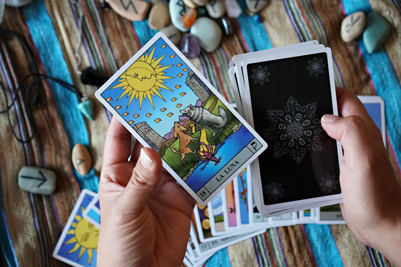 Tarot reading setup with colorful La Luna card highlighted, stones, and runes in the background.