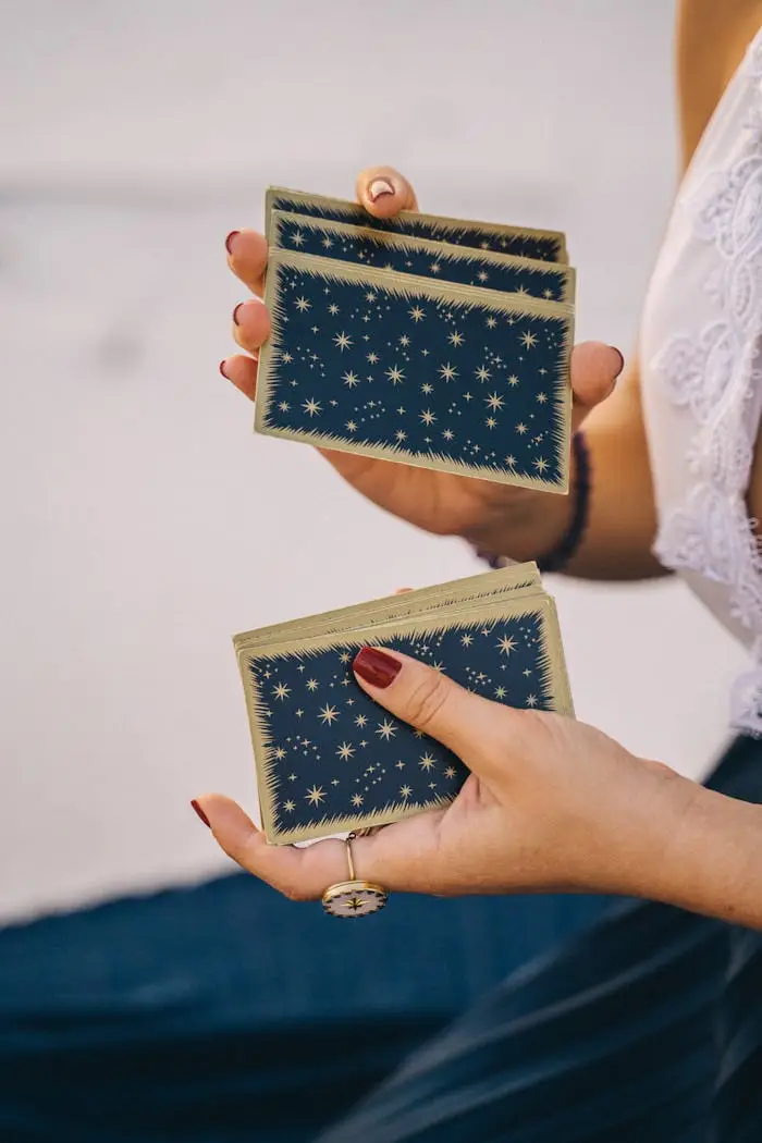 Woman shuffling tarot cards, close-up view, outdoors setting.